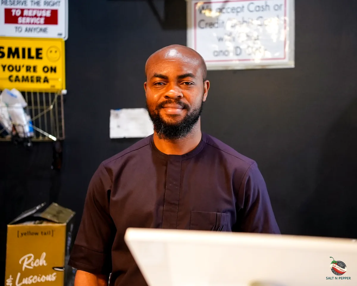 About Us Smiling at the counter at Salt N Pepper Kitchen